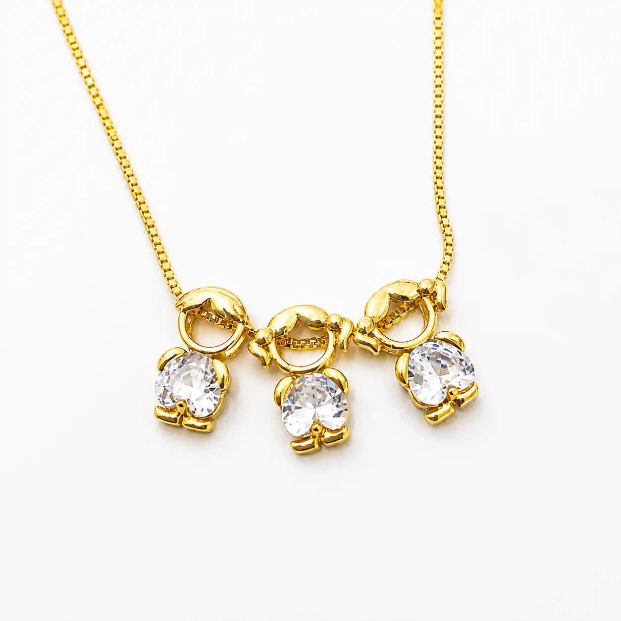 Gold-tone necklace with one boy and two girl figure pendants in white stones